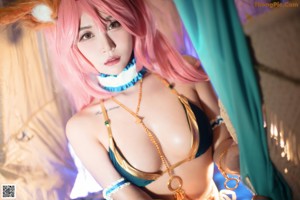 A woman with pink hair in a bikini posing for a picture.