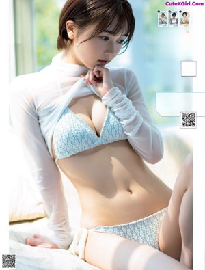 A woman in a blue bikini leaning against a wall.