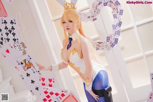 A woman in a bunny costume sitting on a pile of playing cards.