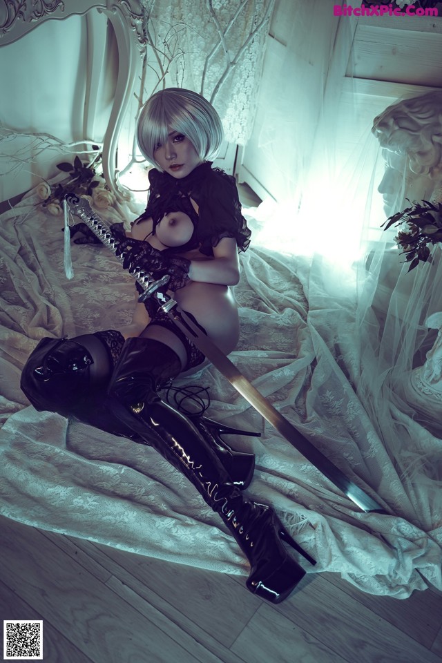 A woman sitting on a bed holding a sword.