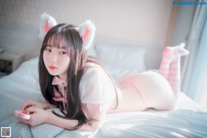 A woman in a pink bikini sitting on a bed.