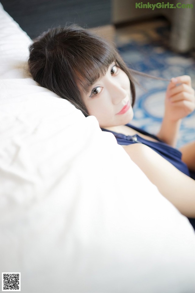 A woman laying on top of a bed next to a pillow.