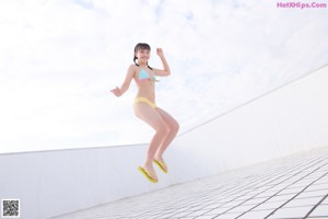 A woman in a bikini standing on a tiled floor.