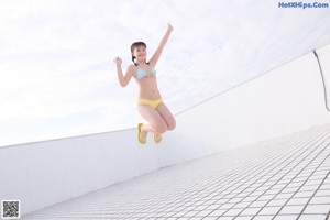 A woman in a bikini sitting on a tiled floor.