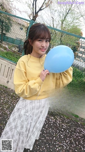 A woman standing in front of a green fence.