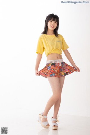 A woman in a yellow shirt and a colorful skirt.