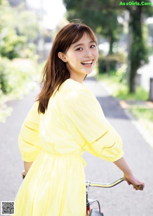 A young woman sitting on the ground with a smile on her face.