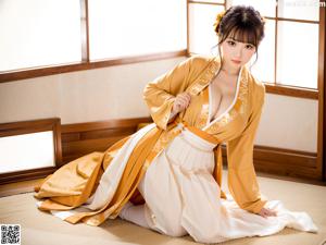 A woman in a green kimono sitting on a wooden floor.