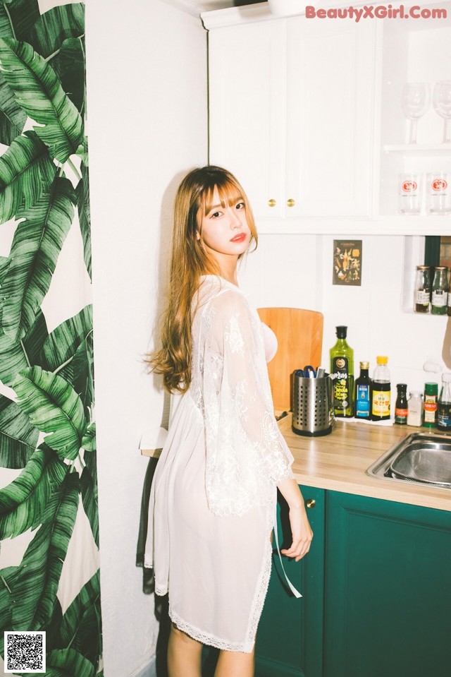 A woman standing in a kitchen next to a sink.