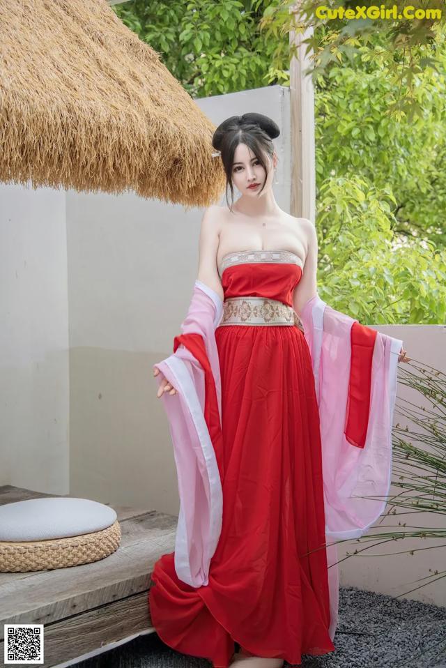 A woman in a red and pink dress posing for a picture.