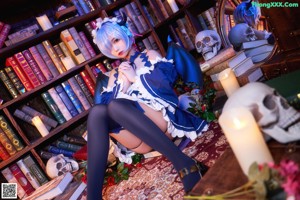 A woman sitting on the floor in front of a book shelf.