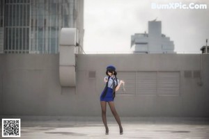 A woman in a blue uniform crouching down on the ground.