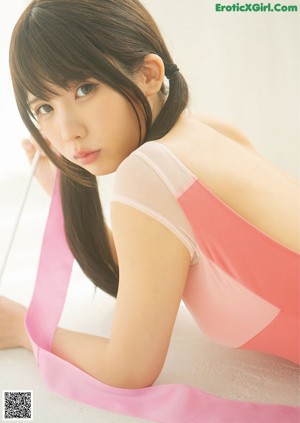 A woman in a pink dress is holding a pink ribbon.