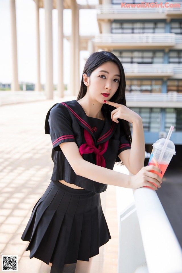 A woman in a school uniform holding a drink.