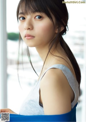 A woman in a green dress leaning against a wall.