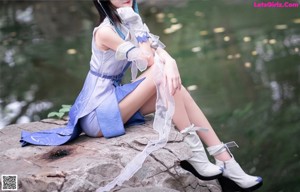 A woman sitting on a rock in the middle of a stream.