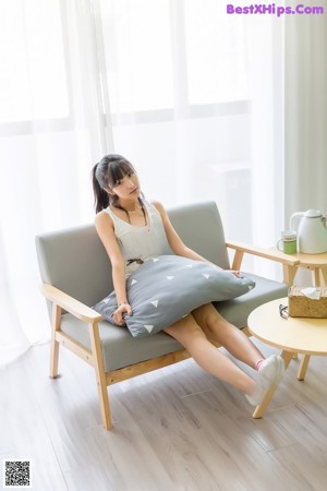 A woman sitting on a pillow with her hand on her chin.