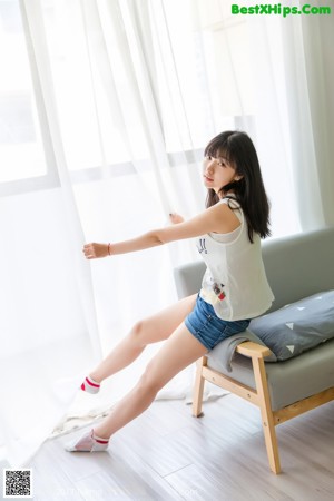 A woman standing on top of a white table next to a window.