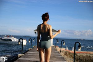 A woman in a black swimsuit standing on the beach.