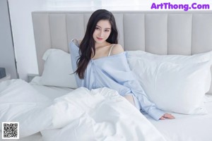 a woman sitting on top of a bed with her legs crossed