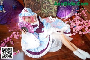 A woman in a pink and green nurse outfit sitting on a bed.