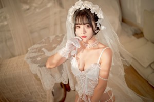 A woman in a white lingerie sitting on a bed.
