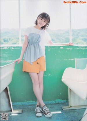 A woman in a green and white dress sitting on a rock.