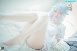 A woman in a white dress sitting on a bed.