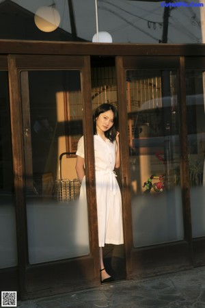 A woman in a white dress sitting on a wooden floor.