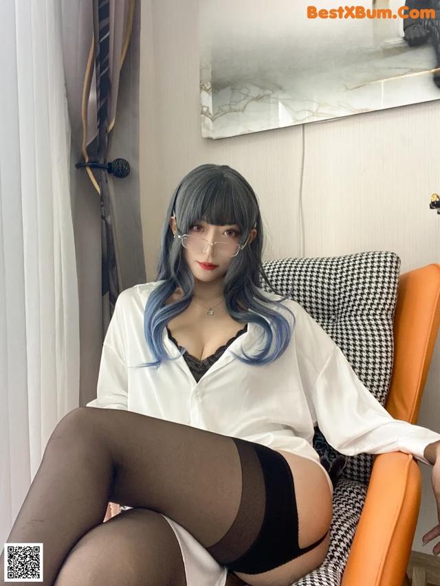 A woman with blue hair sitting on a chair.