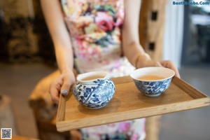 A woman in a floral dress sitting on a chair.