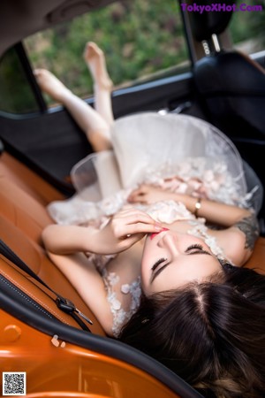 A woman in a short dress standing next to a car.