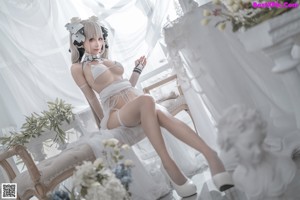 A woman in a white lingerie sitting on a chair.