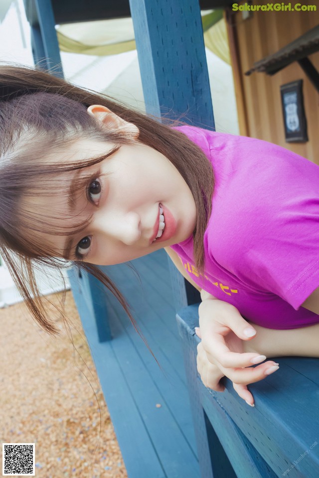 A young girl leaning on a blue bench.