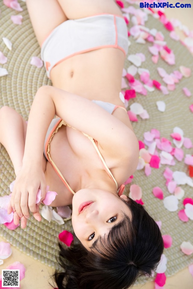 A woman laying on the ground covered in rose petals.