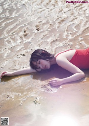 A woman in a bikini sitting on the beach.