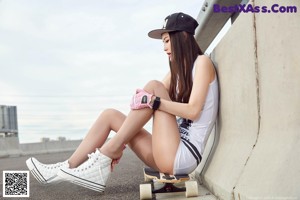 A woman sitting on a skateboard on the ground.