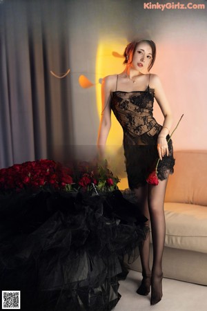 A woman in a black dress holding a blue gun.