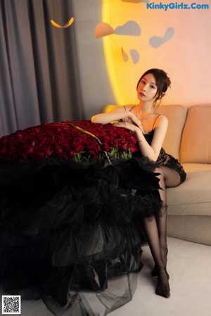 A woman in a black dress holding a bouquet of red roses.